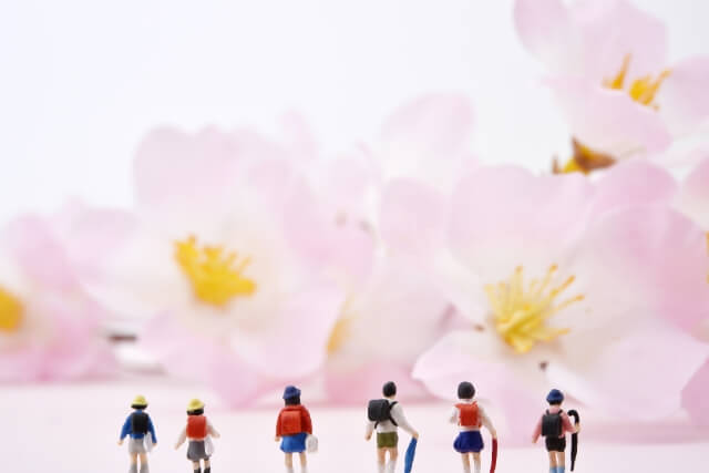 大きな桜の花の群れをバックにそれらを見上げる６人の小学生たち