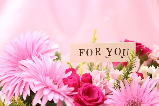 ピンク色の花を集めた花束に添えられた「FOR YOU」のカード