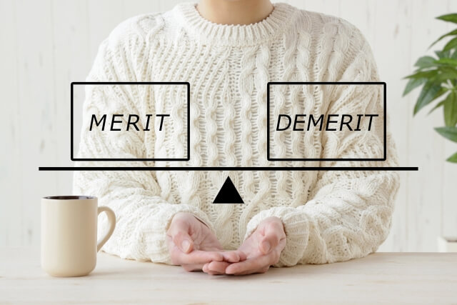 白いセーターを着た女性の心中を表現した「MERIT」と「DEMERIT」とを図る天秤（イメージ）