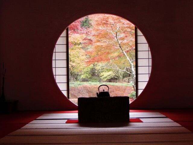 秋の北鎌倉。明月院の圓窓から見える紅葉。手前には火鉢と薬缶。