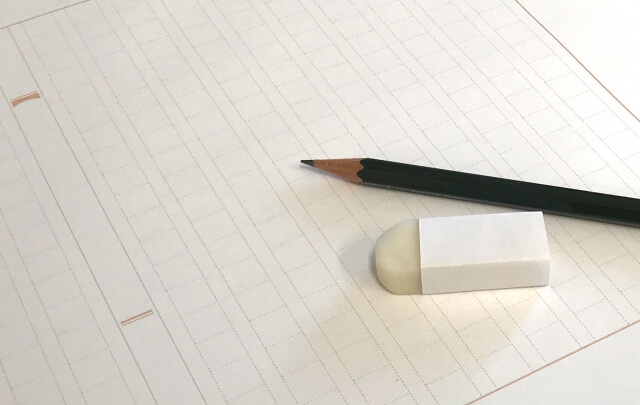 広げられた原稿用紙の上に置かれた鉛筆と消しゴム
